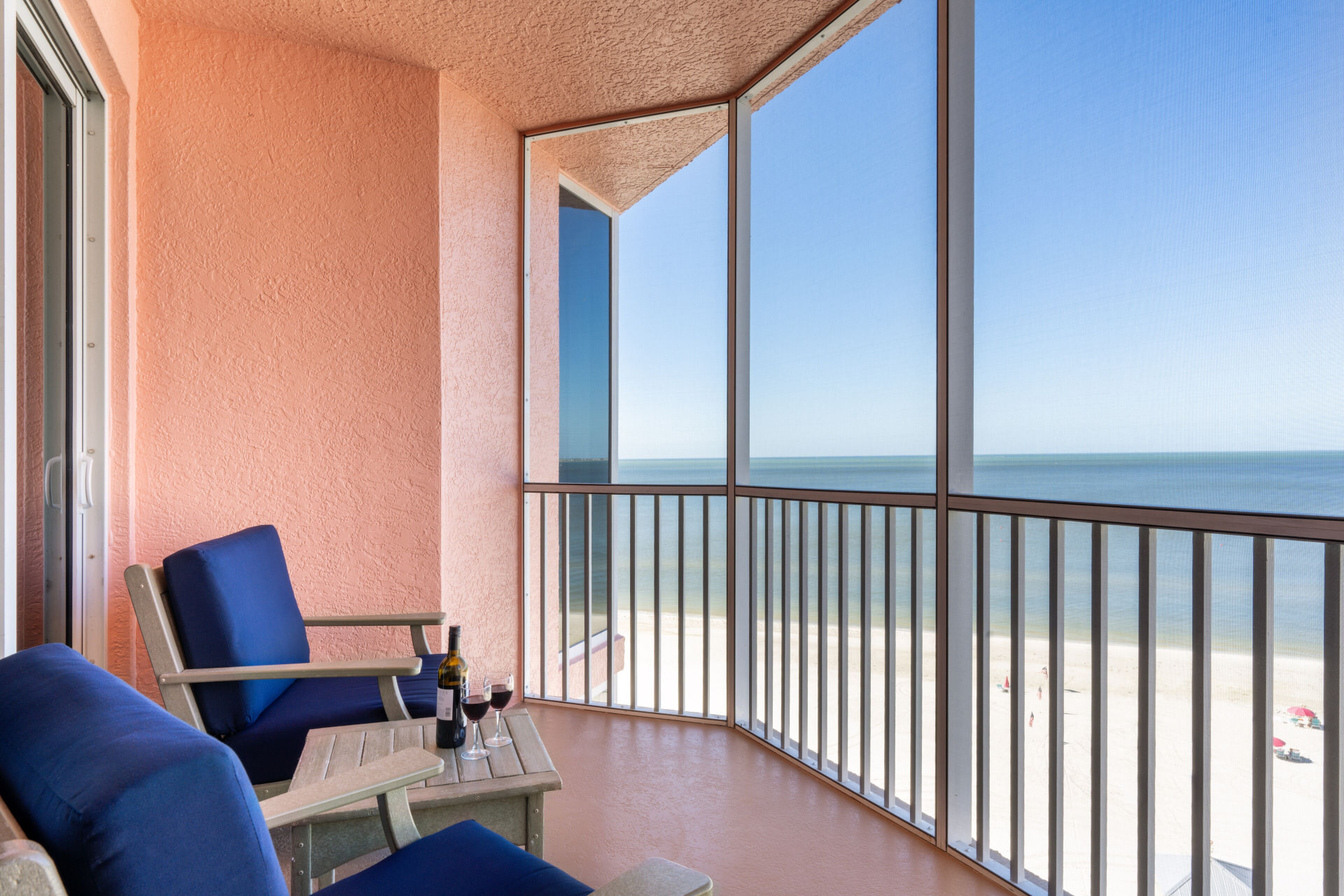 Screened balcony with chairs and wine overlooking Fort Myers Beach at Pink Shell